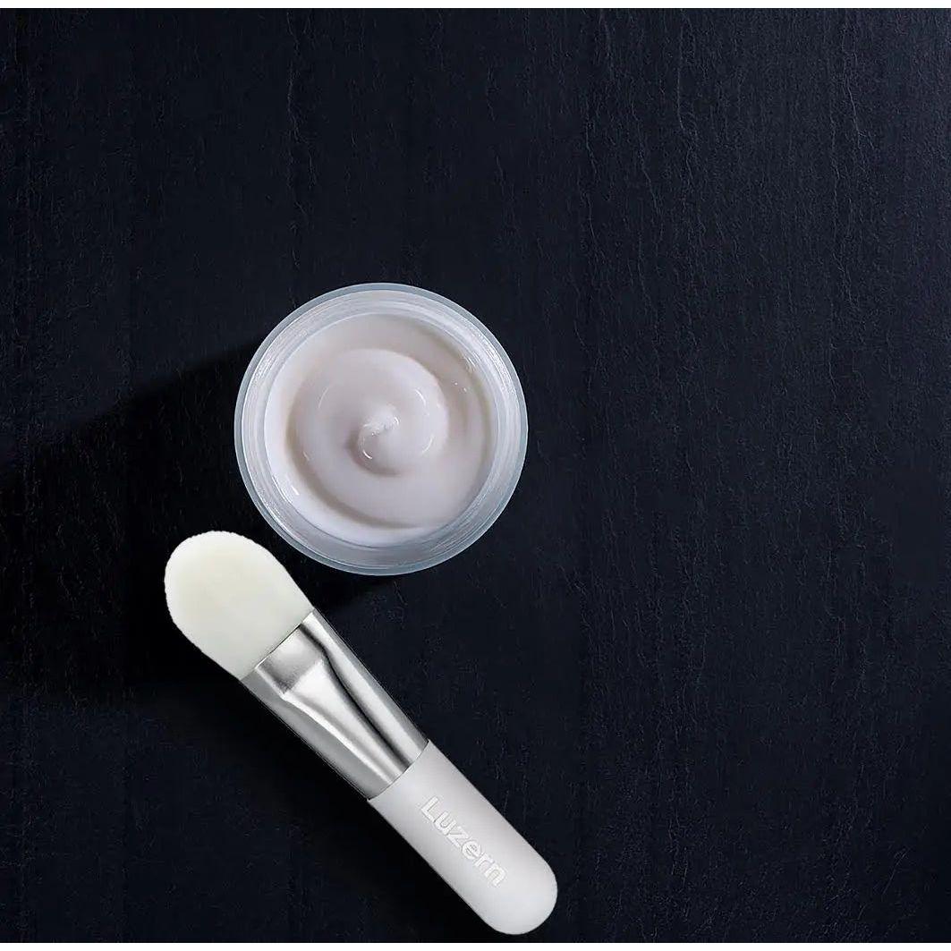 Nuit Hydra Enzyme Masque with application brush on dark background, ideal for hydrating and treating fine lines and wrinkles.