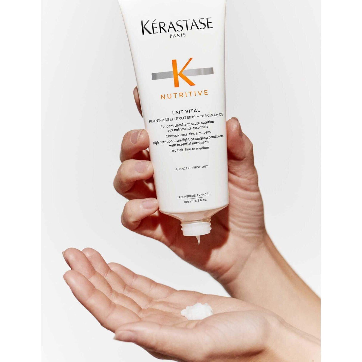 Alt Tag: Kerastase Nutritive Lait Vital Conditioner being poured onto hand for nourishing and detangling dry hair.