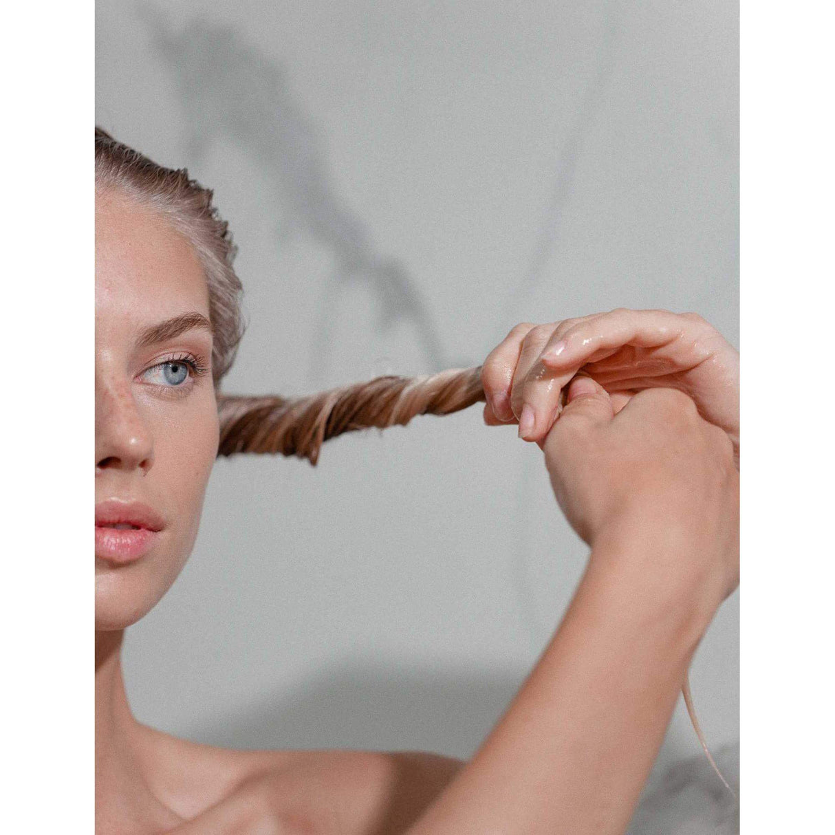 Woman applying Nutritive Lait Vital Conditioner, showing hair strengthening and nourishment.