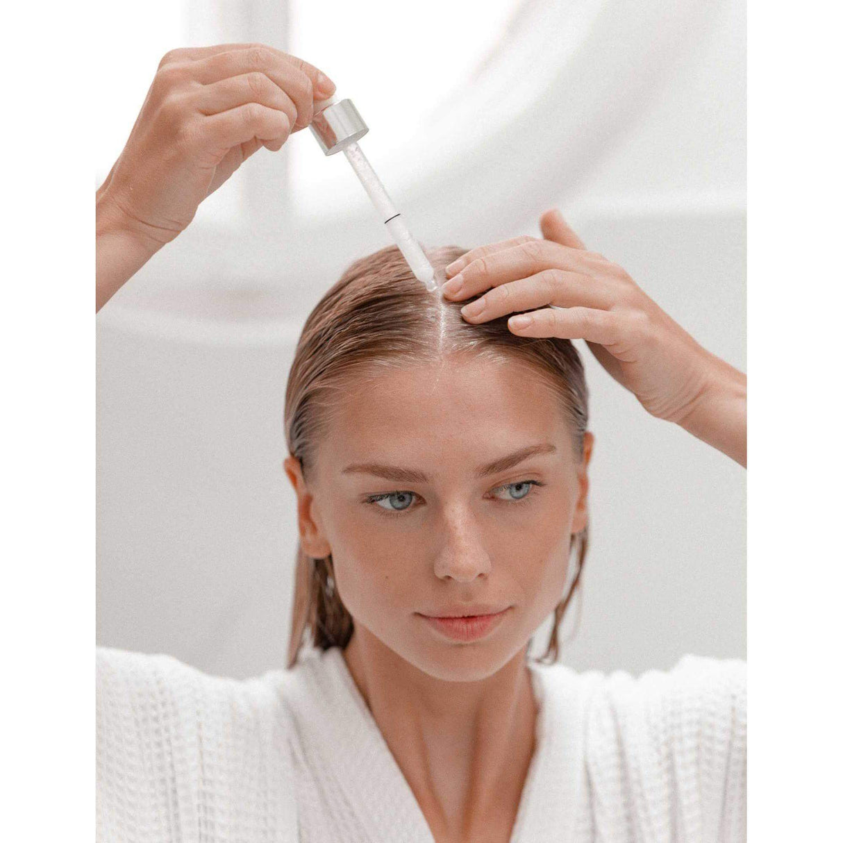 Woman applying Nutritive Nutri-Supplement Scalp Serum to dry scalp for nourishment and hydration.