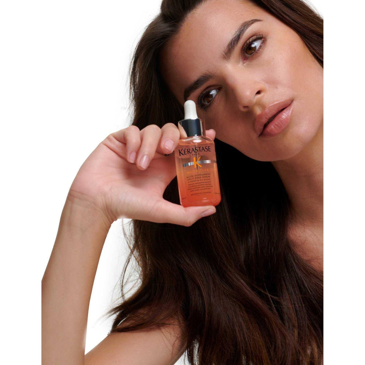 Woman holding Kérastase Nutri-Supplement Split Ends Serum for dry, split-end hair nourishment and sealing.