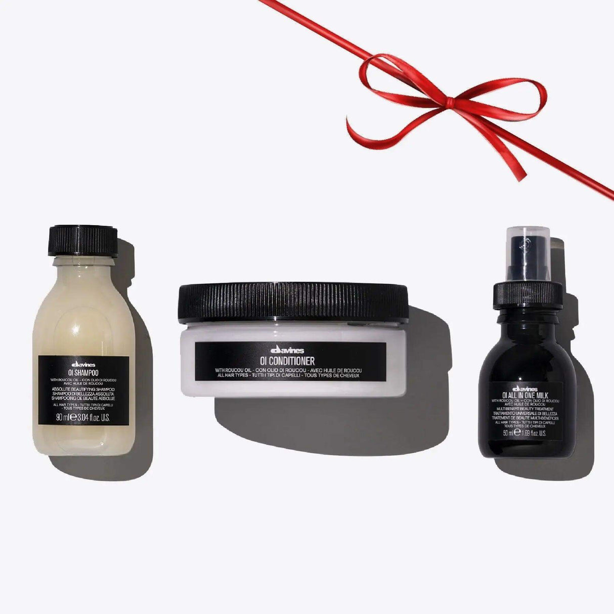 Oi Travel Set with Shampoo, Conditioner, All in One Milk for nourishing and shiny hair, travel-sized hair care products with red ribbon.
