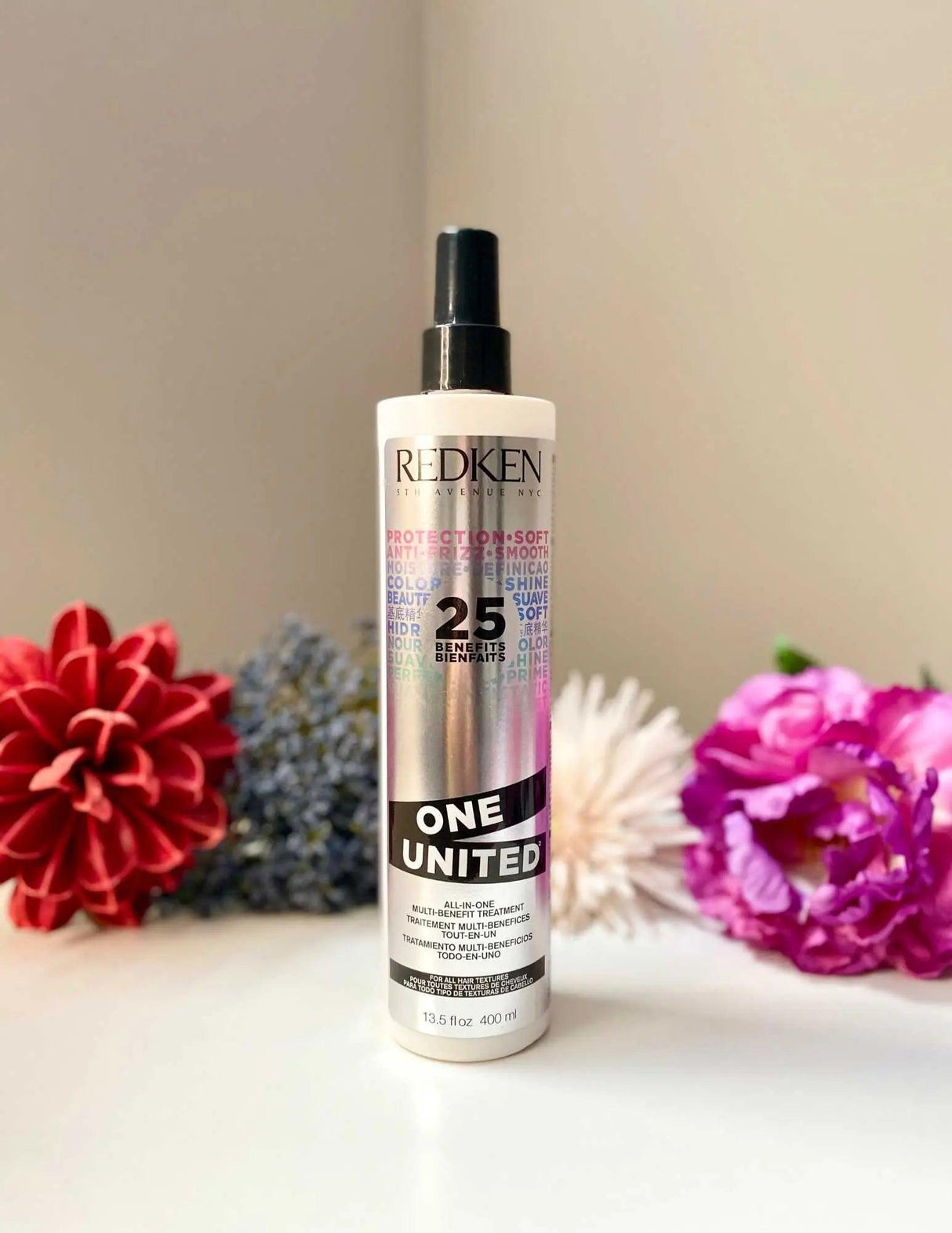Redken One United bottle with colorful flowers, multifunctional hair treatment for all types, addressing dryness, damage, and frizz.