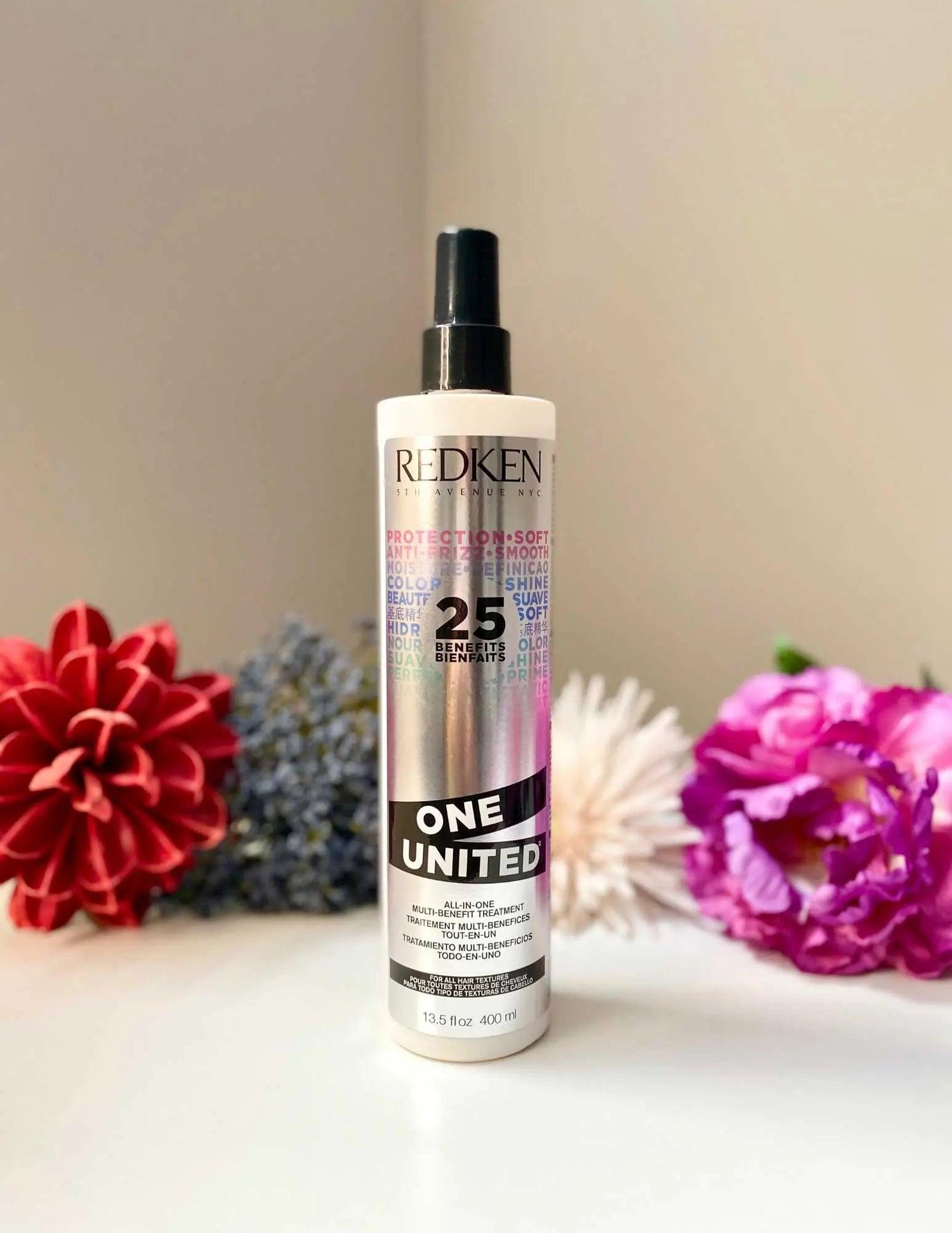 Redken One United bottle with colorful flowers, multifunctional hair treatment for all types, addressing dryness, damage, and frizz.
