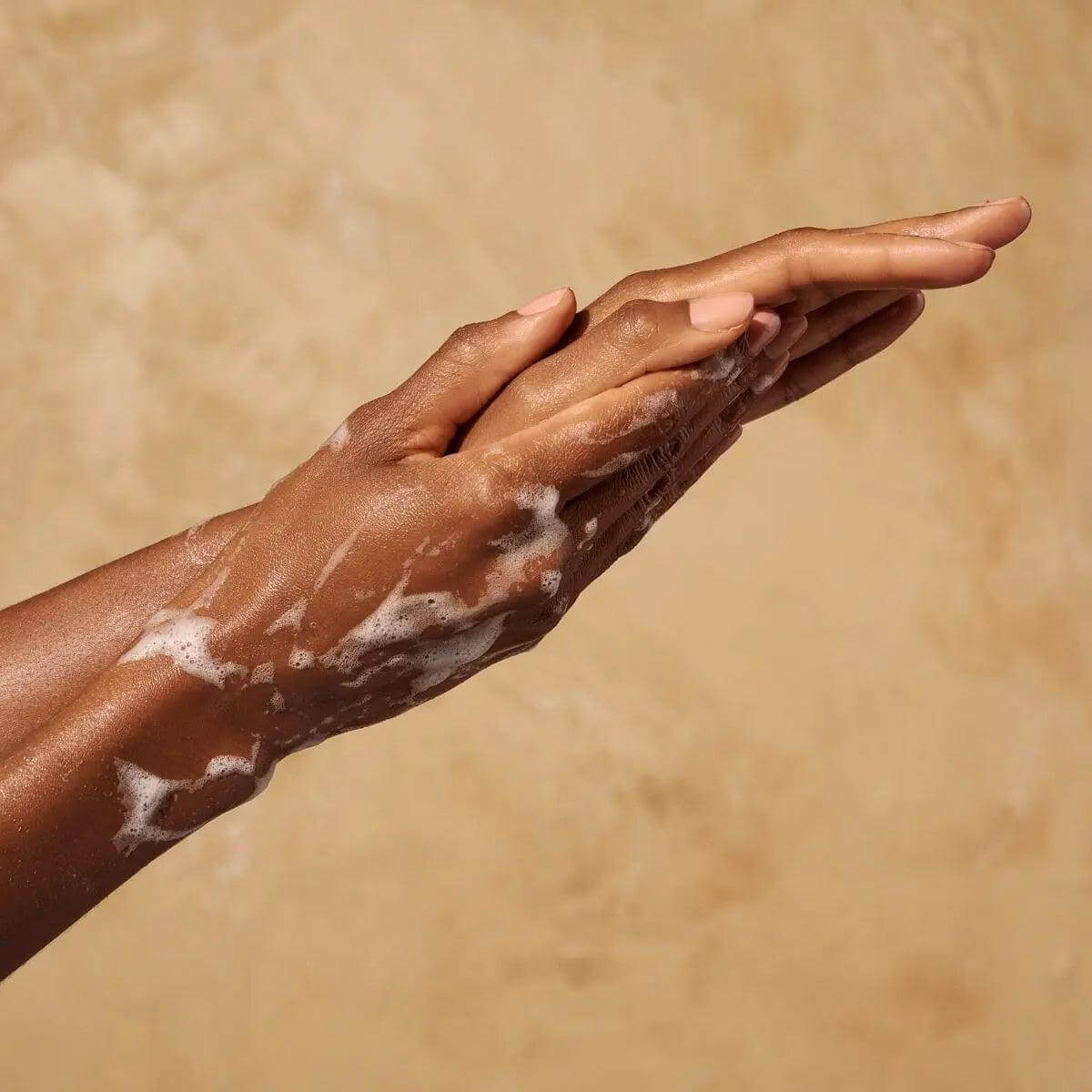 Hands with foamy Originale Fragrance Hand Wash, enriched with argan oil and hyaluronic acid, showcasing gentle cleansing.