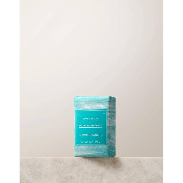 Moroccanoil Originale Fragrance Soap Bar with argan oil and shea butter, providing intense moisture and hydration, displayed on a countertop.