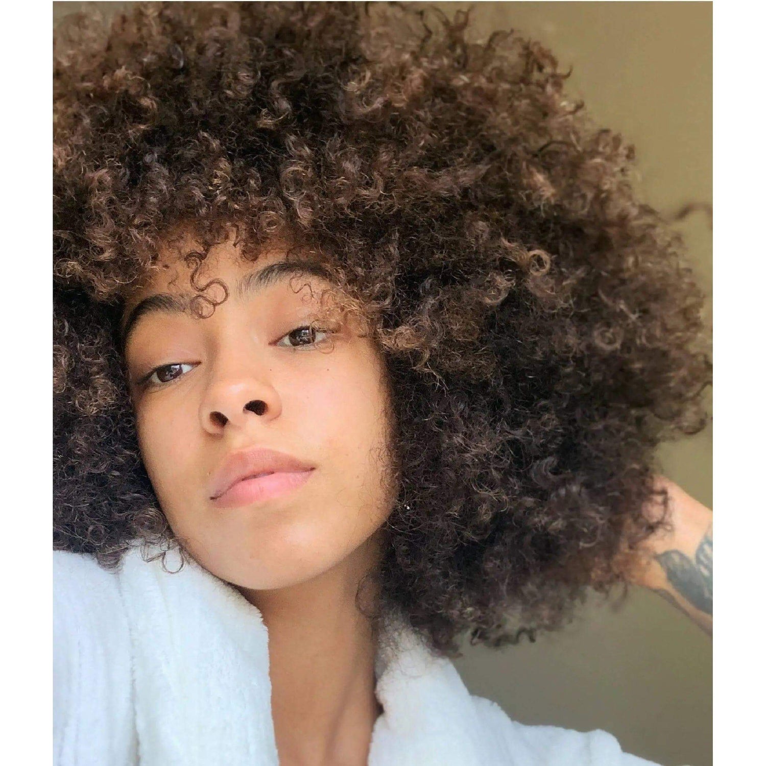 Person with naturally curly hair wearing a white robe, showcasing hydrated and voluminous curls.