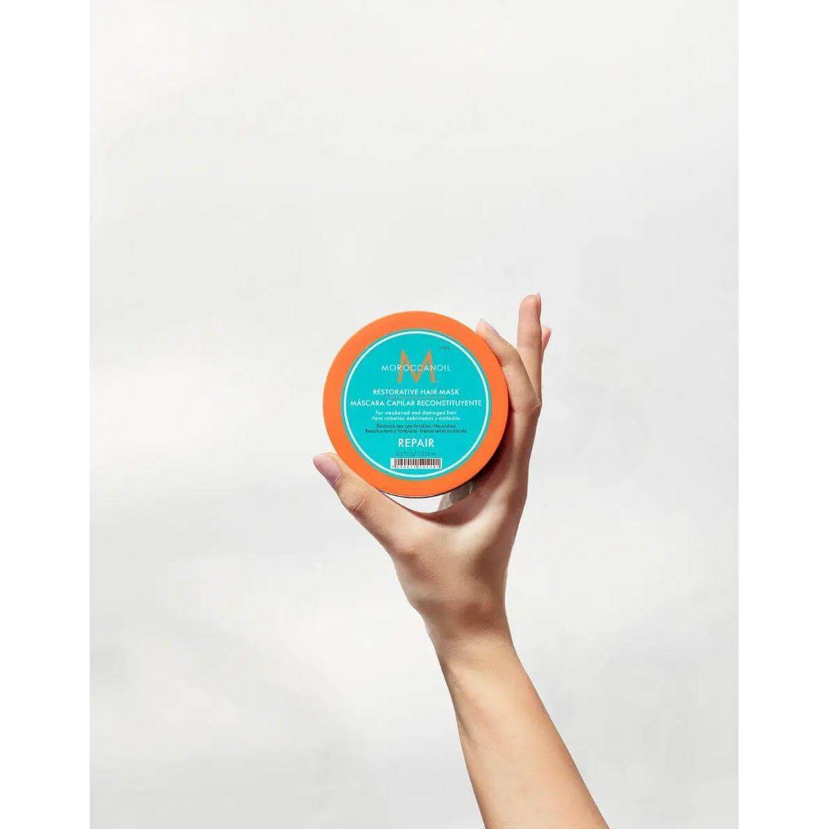 Hand holding Restorative Repair Hair Mask jar, ideal for dry and damaged hair, offers deep repair and moisture with protein infusion.