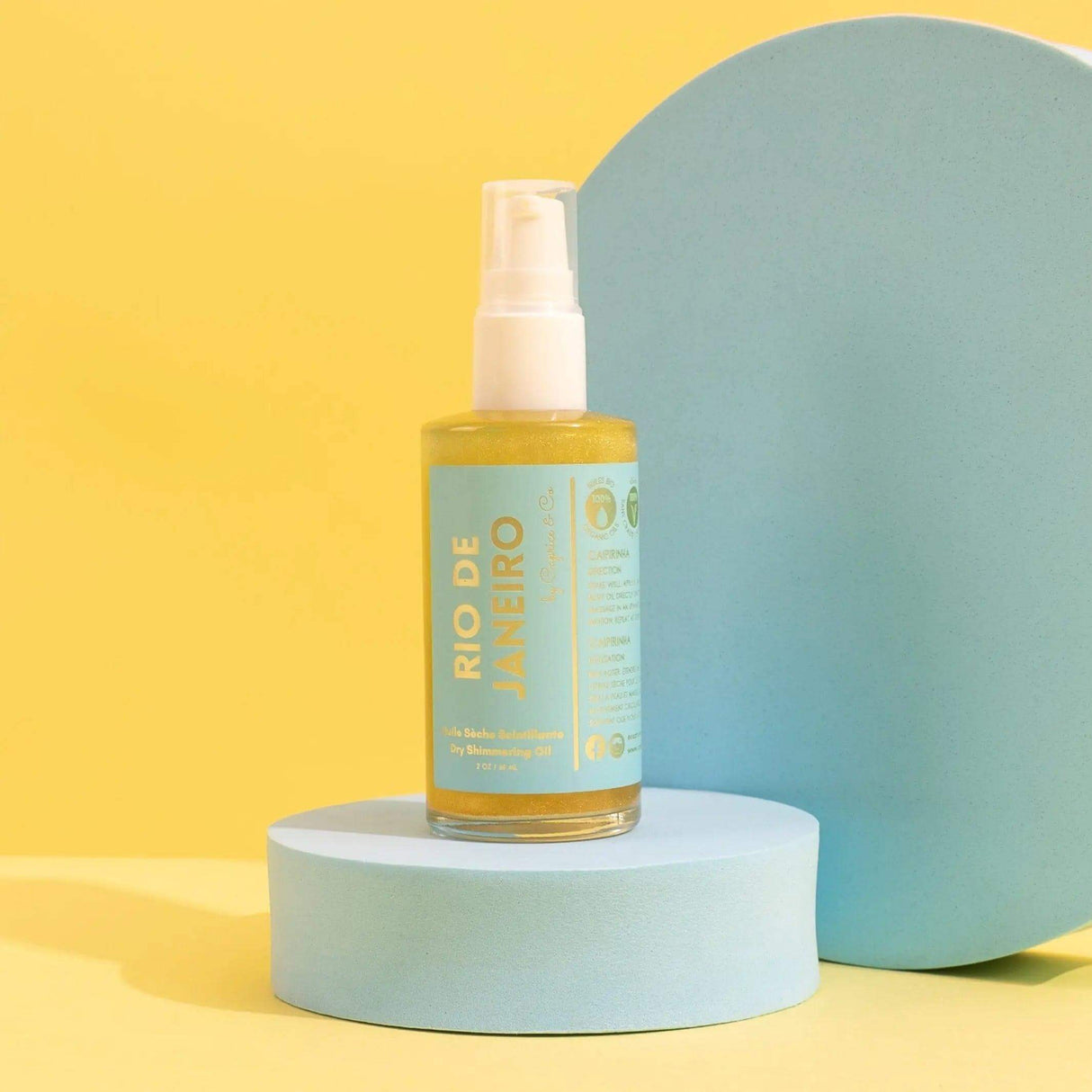 Rio De Janeiro Dry Shimmering Oil bottle on display, 2 oz size, yellow gold color, featuring organic coconut oil for a radiant glow.
