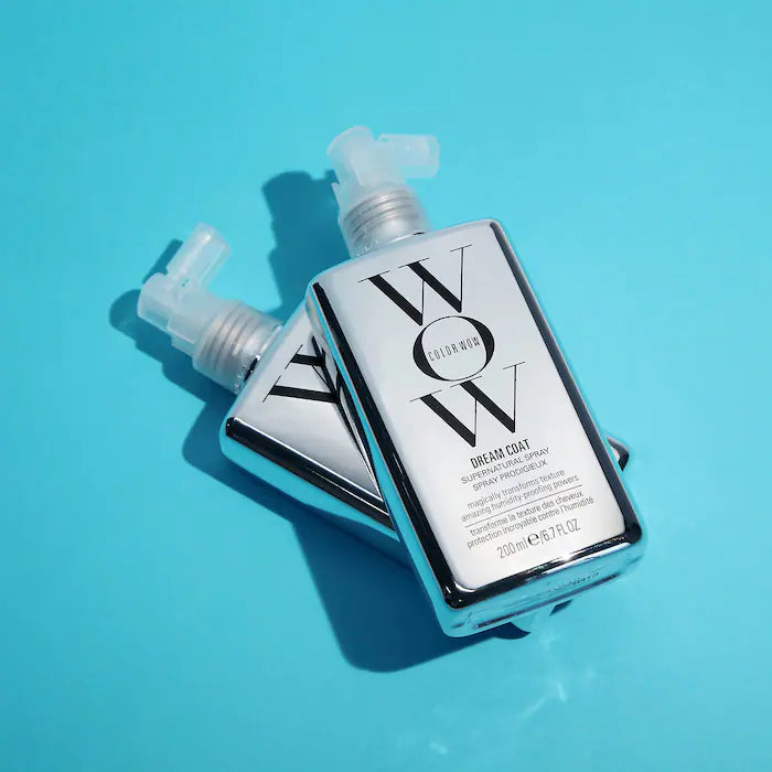 Dream Coat Supernatural Spray bottles on blue background, anti-frizz treatment with glossy finish for ultra-smooth hair.