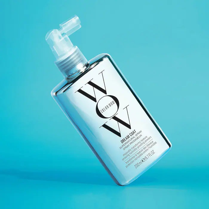 Dream Coat Supernatural Spray bottle against blue background; anti-frizz treatment with humidity-blocking technology.