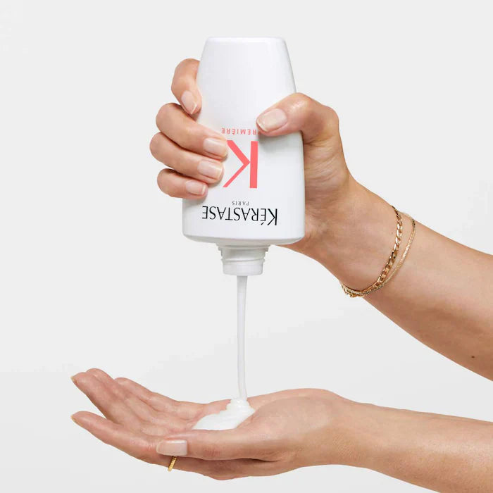Person pouring Bain Décalcifiant Réparateur Shampoo onto hand, showcasing creamy texture for damaged hair treatment.