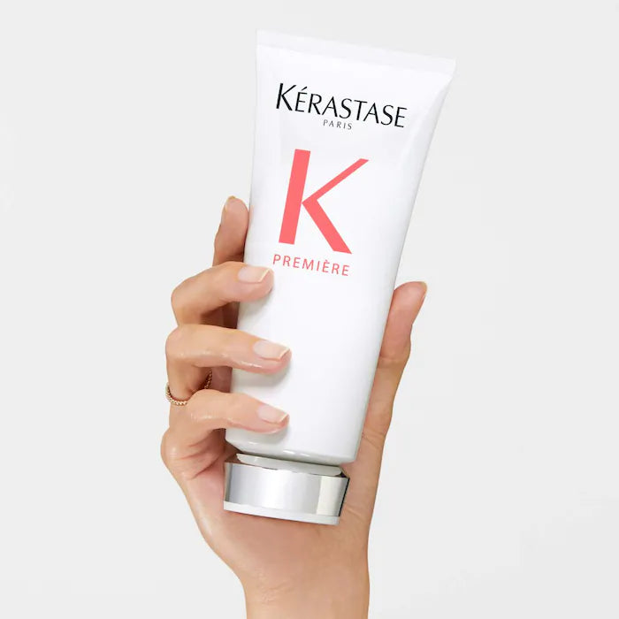 Hand holding Kérastase Fondant Fluidité Réparateur Conditioner for damaged hair repair and moisture rejuvenation.