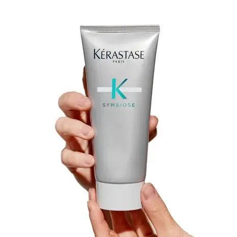 Person holding Kerastase Scalp Purifying Micro-Peeling Scrub, designed to exfoliate and refresh all hair types and textures.