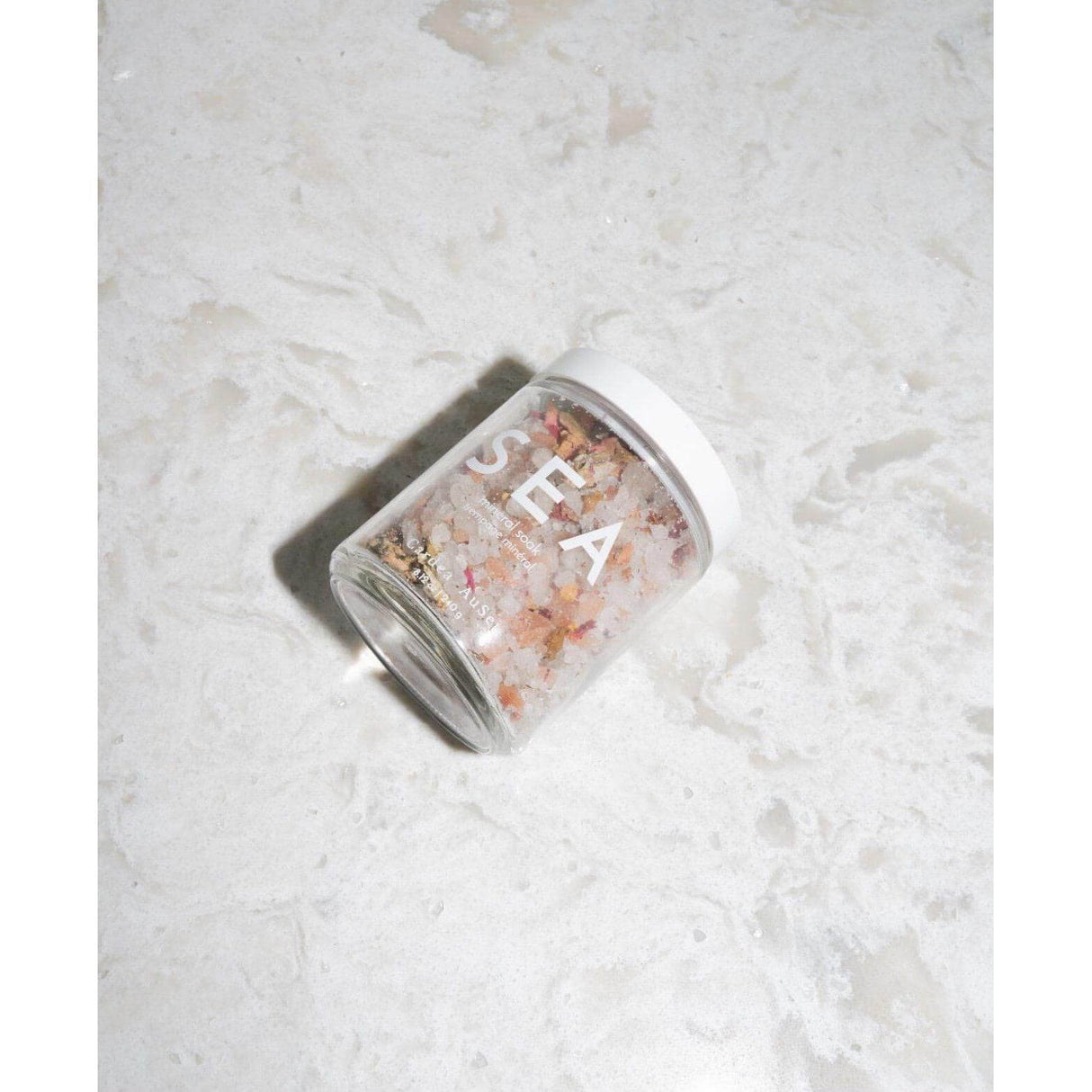 Jar of Sea Mineral Soak with Dead Sea and Himalayan salts and rose petals on marble surface