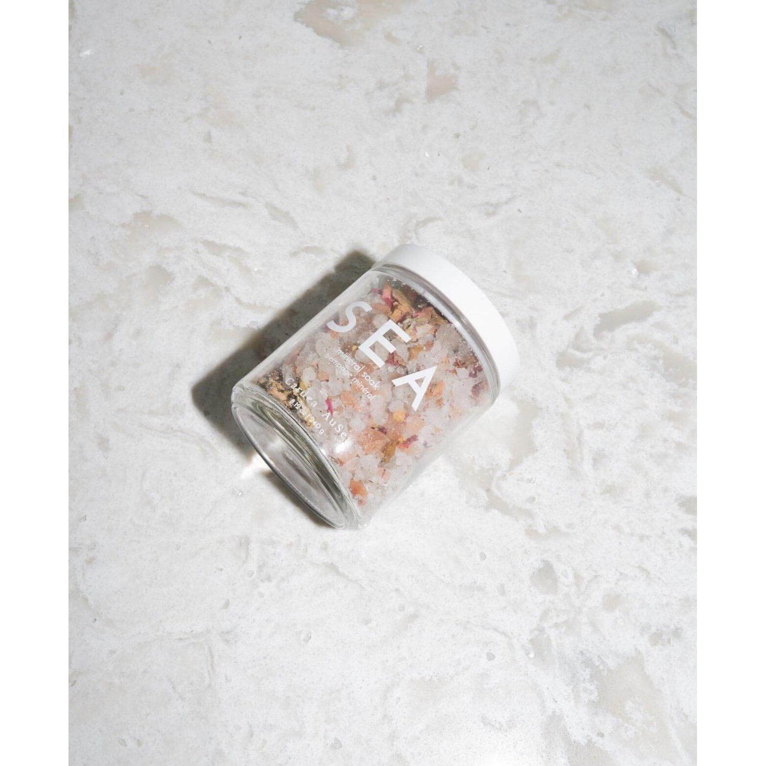 Jar of Sea Mineral Soak with Dead Sea and Himalayan salts and rose petals on marble surface