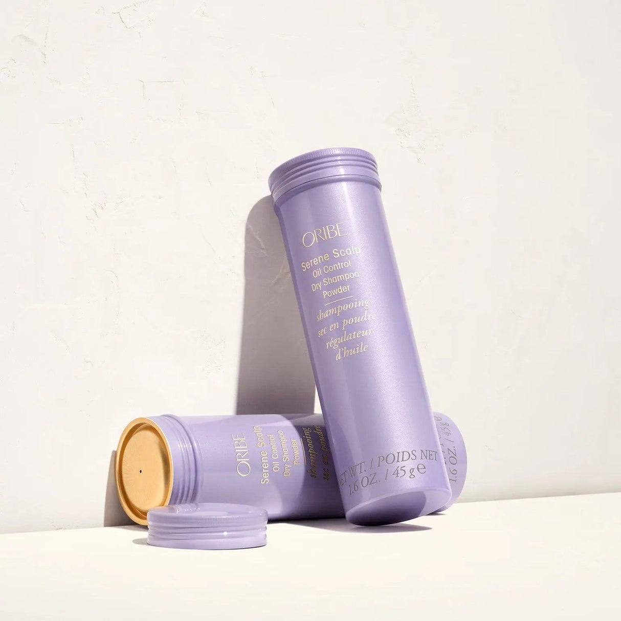 Purple bottles of Serene Scalp Oil Control Dry Shampoo Powder by Shu Uemura against a light backdrop.