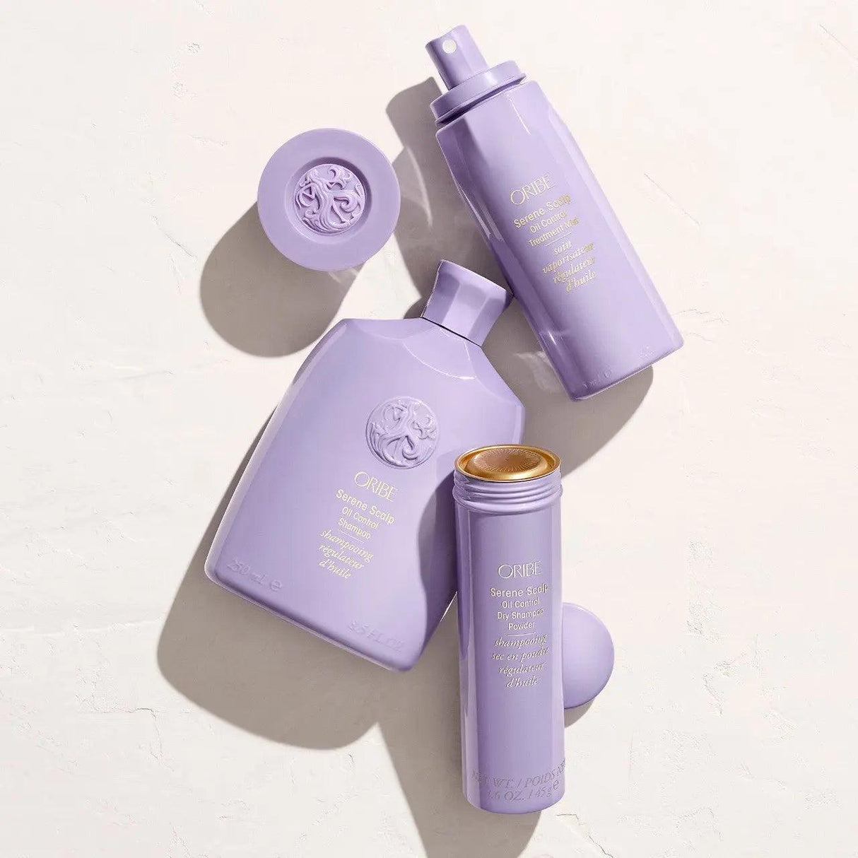 Oribe Serene Scalp Oil Control Shampoo and Conditioner set in purple bottles on a flat surface, suitable for oily scalps and all hair types.