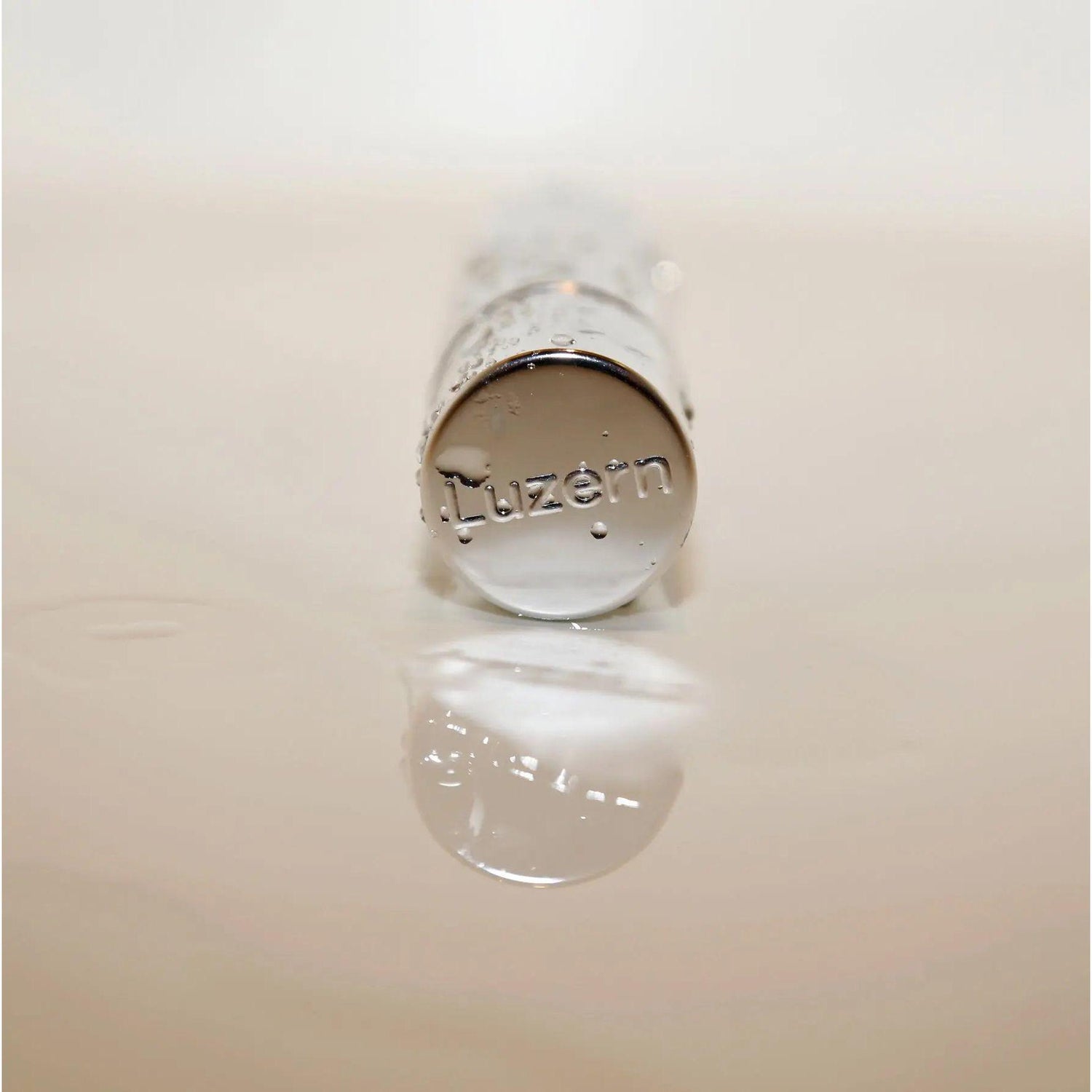 Luzern Serum Absolut Firming Booster bottle with reflective cap on a smooth surface, showcasing premium skincare packaging.
