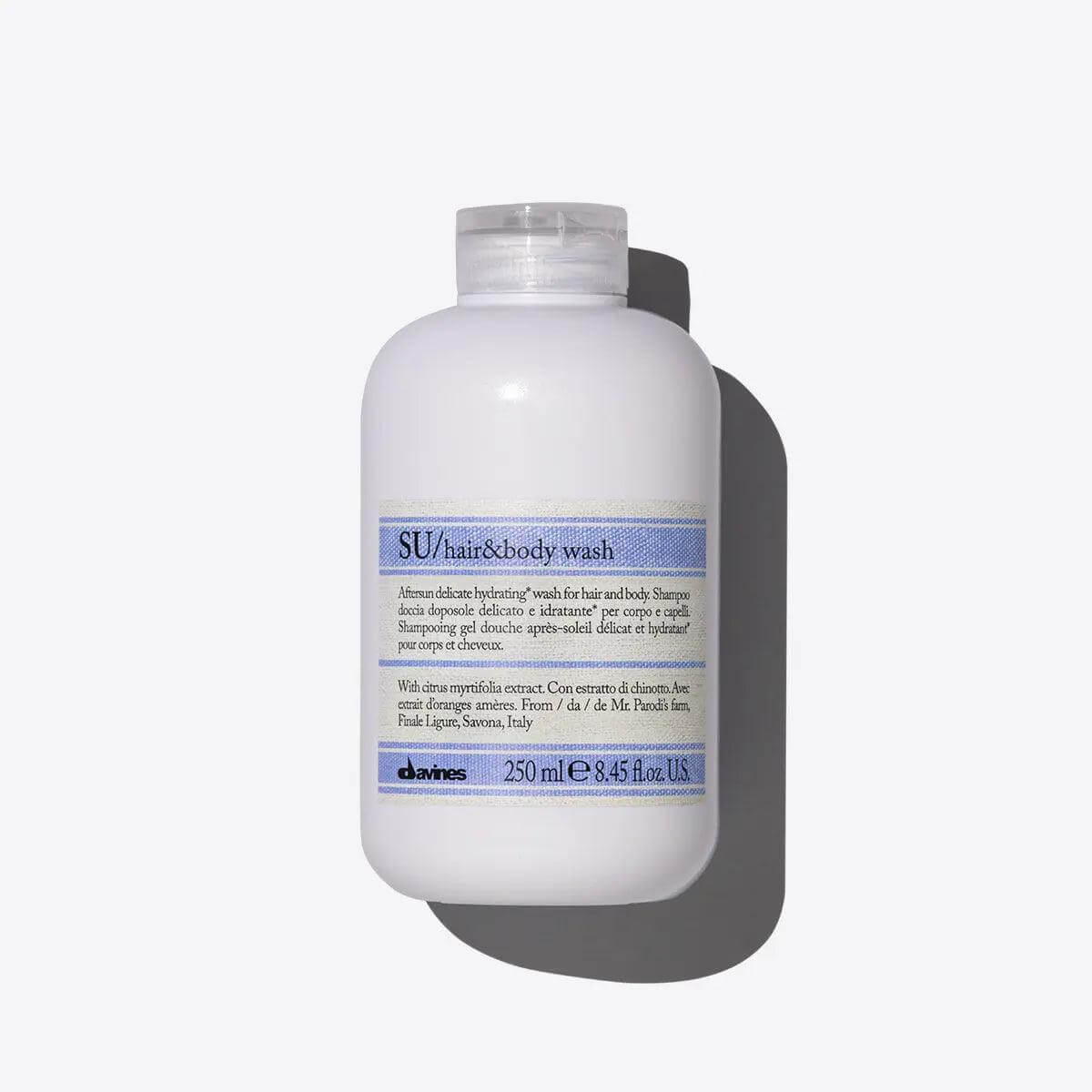 Davines SU Hair & Body Wash bottle on a gray background, hydrating shampoo with antioxidant properties for sun-exposed hair and skin.