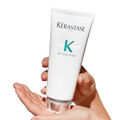 Kerastase Symbiose Fondant Apaisant Essentiel conditioner for soothing sensitive scalps, held in hands against a white background.