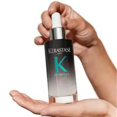 Kerastase Symbiose Sérum Nuit Intensif held in hand, rejuvenates and revitalizes all hair types, perfect for damaged hair.