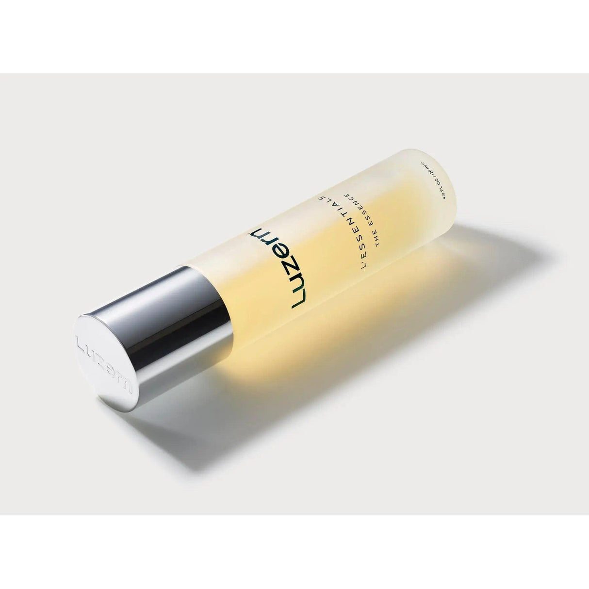 Luzern The Essence revitalizing essence bottle with silver cap, enriched with Swiss extracts and ceramides for skin hydration and nourishment.