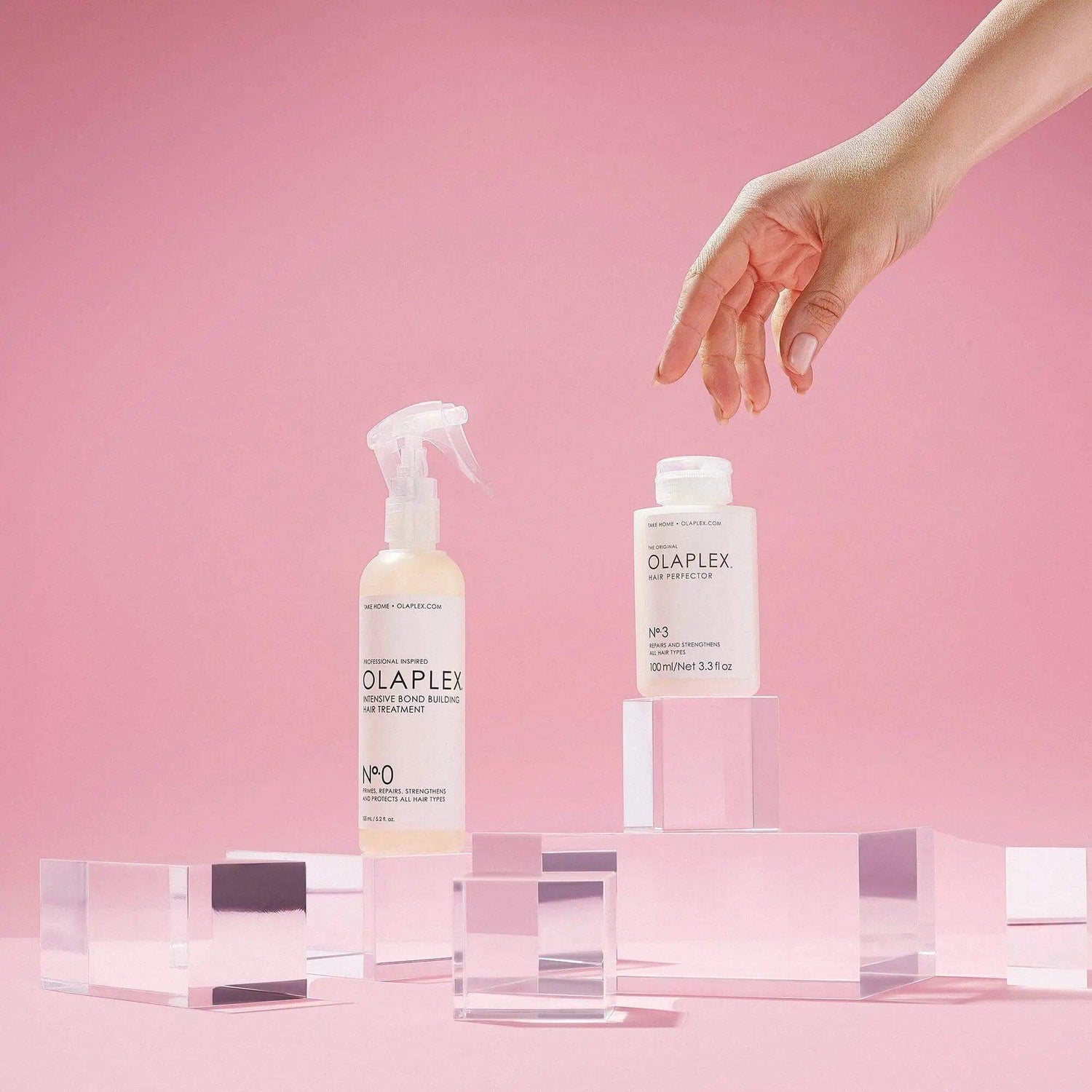 Olaplex Ultimate Repair Kit with No.0 and No.3 Bond Building Treatments on pink background.