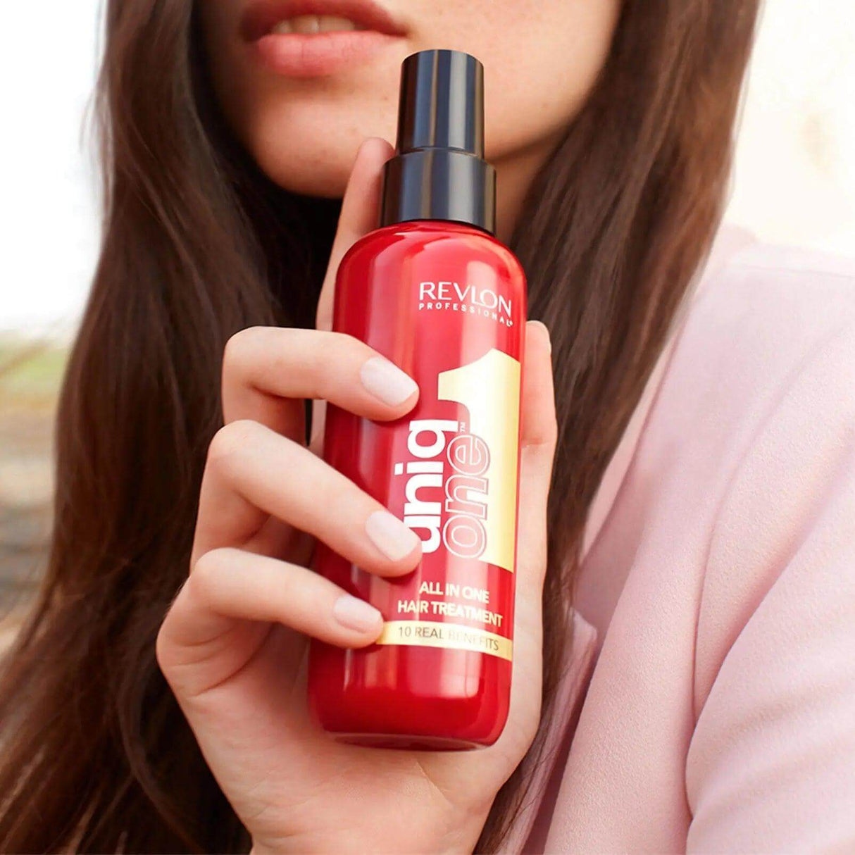 Alt Tag: Woman holding Uniqone™ Hair Treatment bottle, a versatile leave-in hair product for all hair types, offering 10 essential benefits.