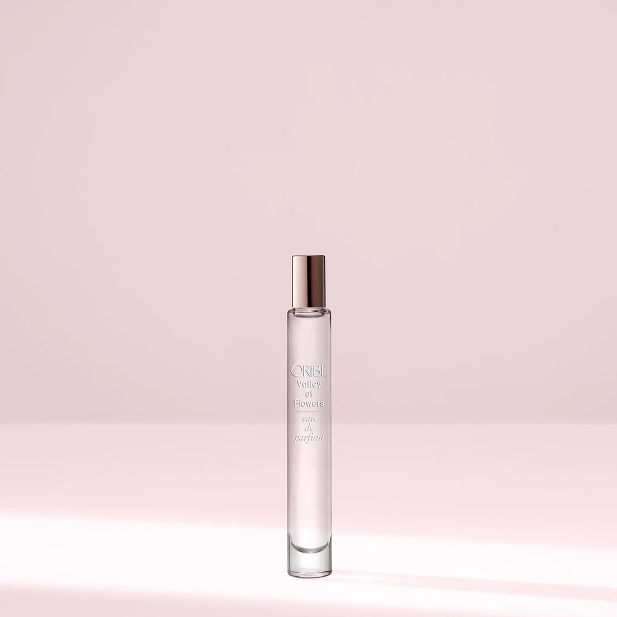 Valley Of Flowers Eau De Parfum bottle against a soft pink background capturing essence of blooms with amber and musk notes.