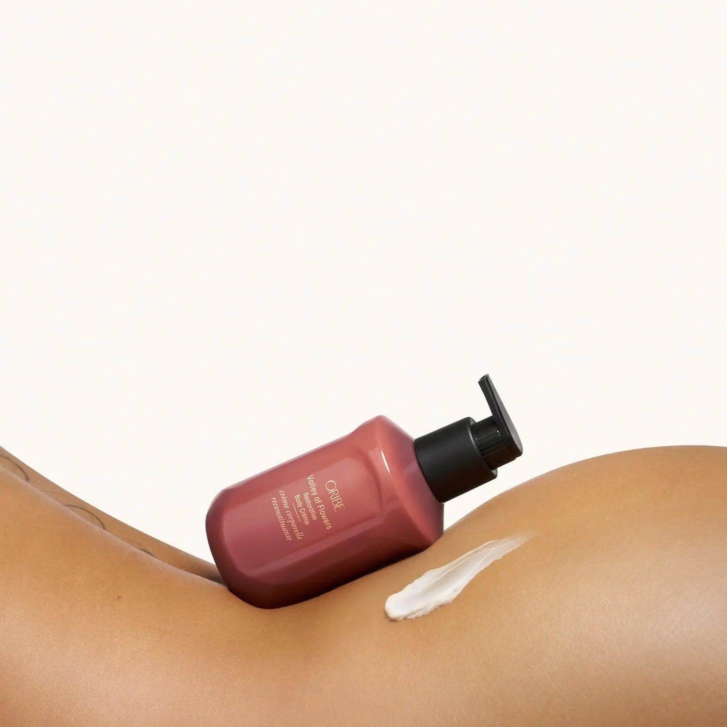 Valley of Flowers Restorative Body Crème by ORIBE on skin, showcasing hydration and smooth finish, 300 ml bottle.