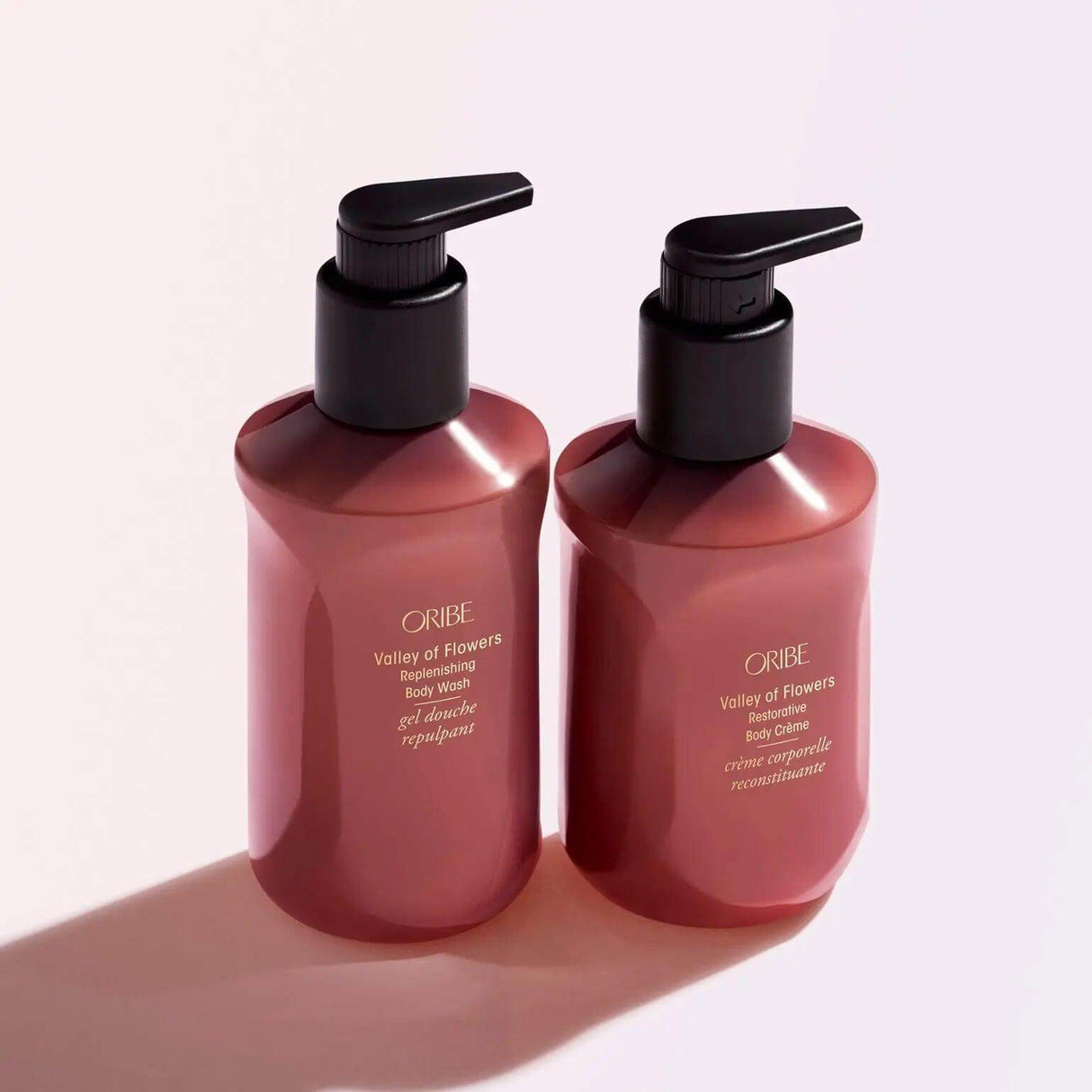 ORIBE Valley of Flowers Body Crème and Body Wash in pink bottles with pump dispensers.