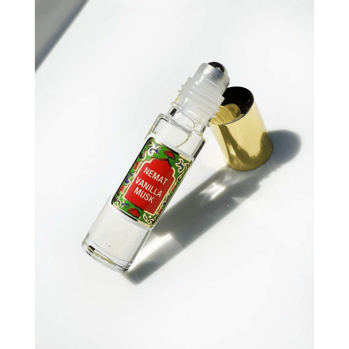 Vanilla Roll On Perfume with a gold cap lying on a white surface, Nemat Vanilla Musk label visible on the bottle.