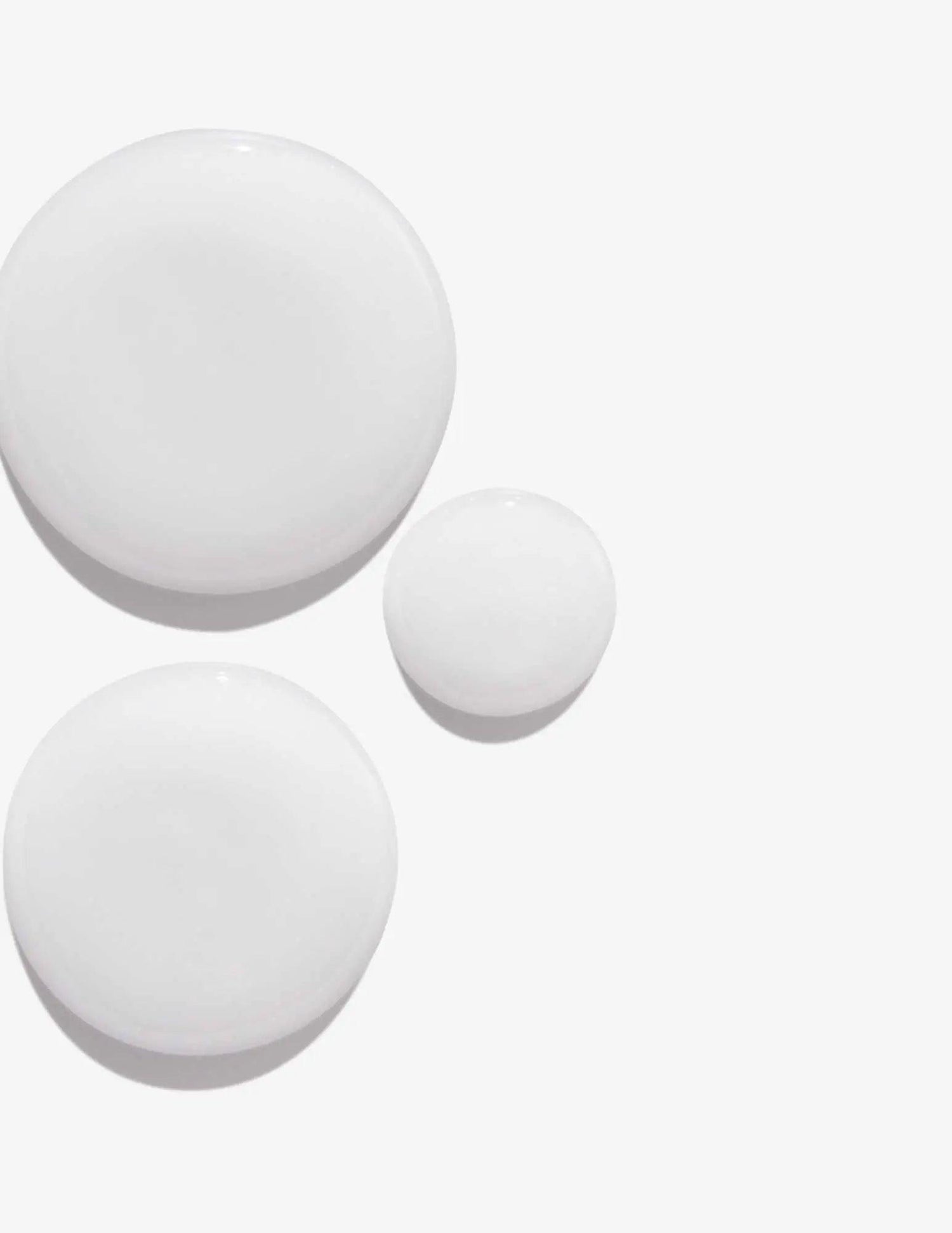 Close-up of shampoo texture in three droplets showcasing creamy consistency on a white background
