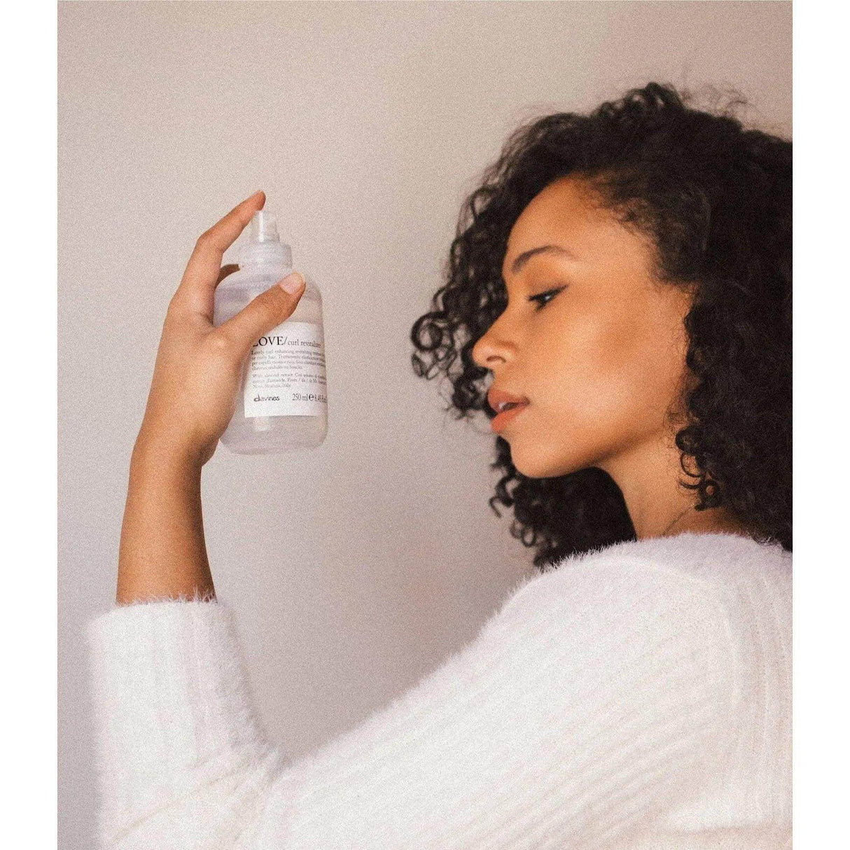 Woman with curly hair holding LOVE Curl product, demonstrating wash and go curls hair care routine.