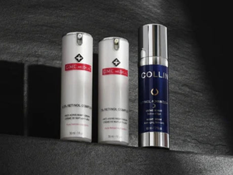 Three skincare product bottles casting shadows on textured surface.