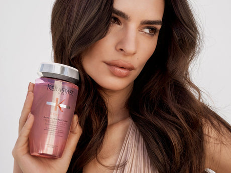 Person holding haircare product, looking calmly at the camera.