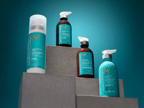 Haircare products displayed on ascending gray blocks, teal backdrop.
