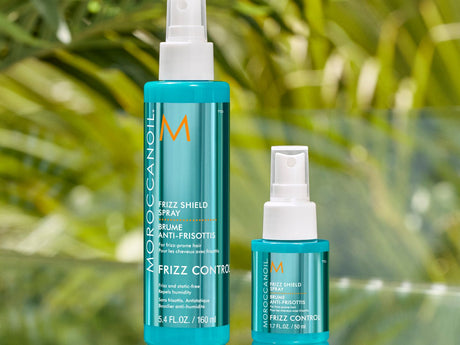 Hair care products displayed with a tropical foliage background.