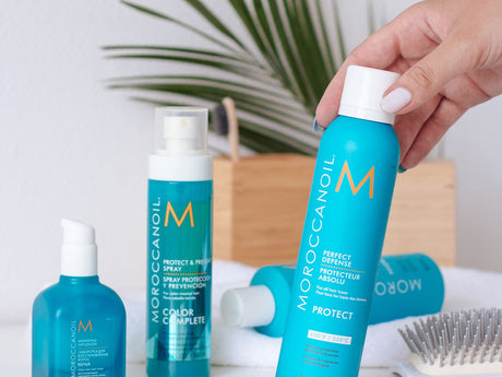 Haircare products displayed with a hand holding a spray bottle.