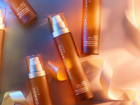 Cosmetic bottles with golden hues and reflective light. Moroccanoil products.