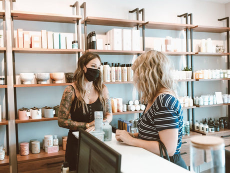 Two people in a shop with shelves of beauty products.
