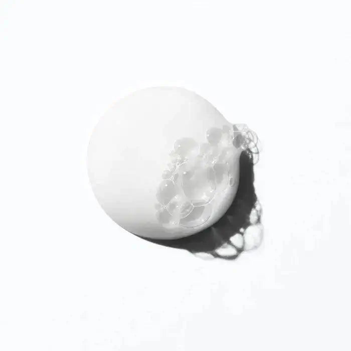 Texture sample of Curl Manifesto Bain Hydration Douceur sulfate-free shampoo with light bubbles, ideal for curly and coily hair.