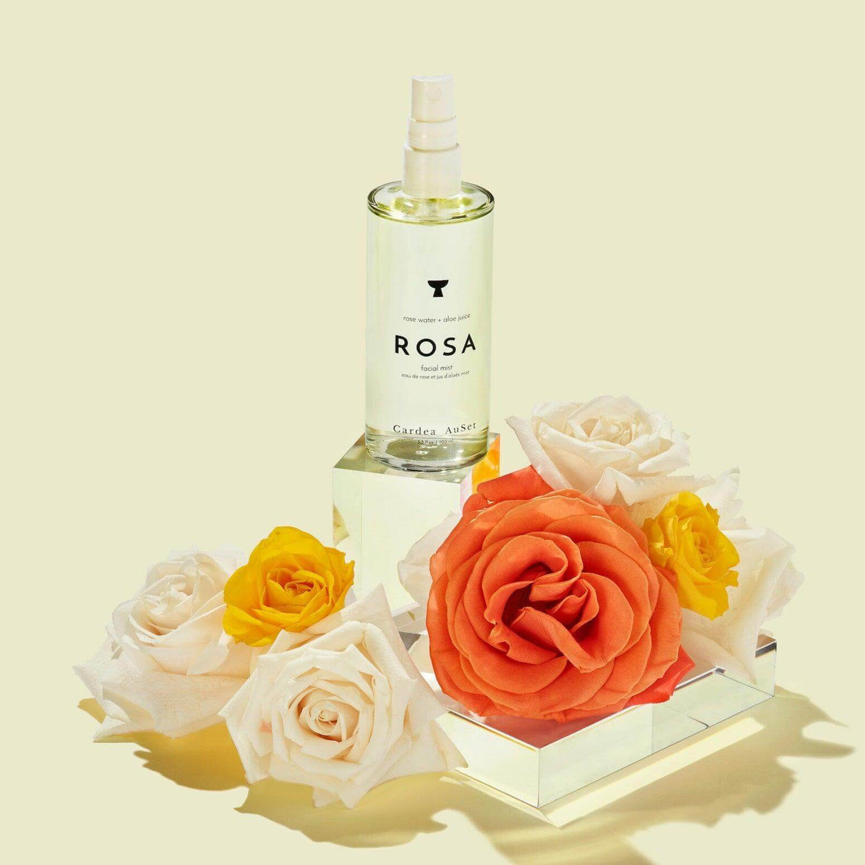 Rosa Facial Mist bottle surrounded by roses, showcasing its hydrating and refreshing properties with rose water and aloe.