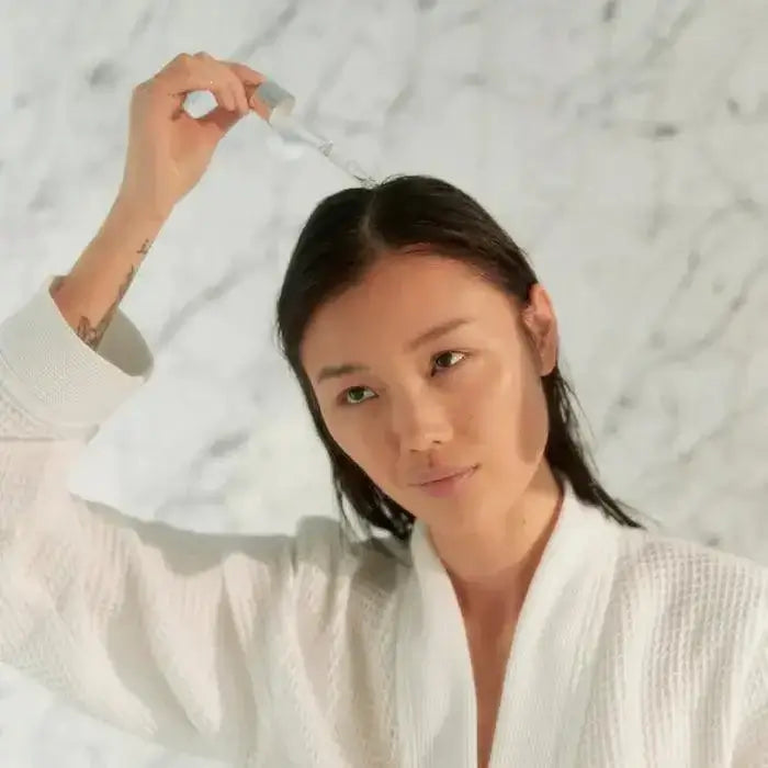 Person applying Kérastase Potentialiste Hydrating Scalp Serum to hair for soothing and hydration.