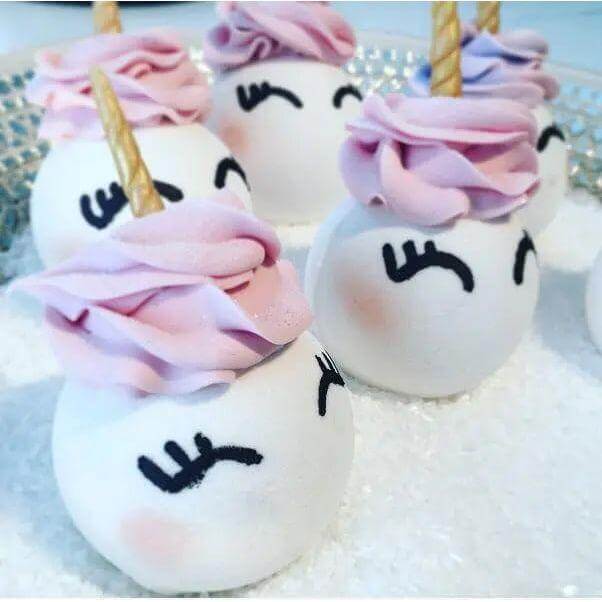 Uni-Bomb XL unicorn-shaped bath bombs with pink and purple frosting and golden horns, featuring peach, lily, and grapefruit fragrance.