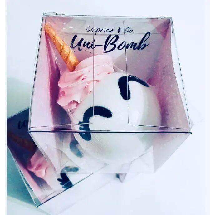 Uni-Bomb XL unicorn-shaped bath bomb with peach, lily, and grapefruit fragrance, packaged in a clear box, perfect for skin soothing.
